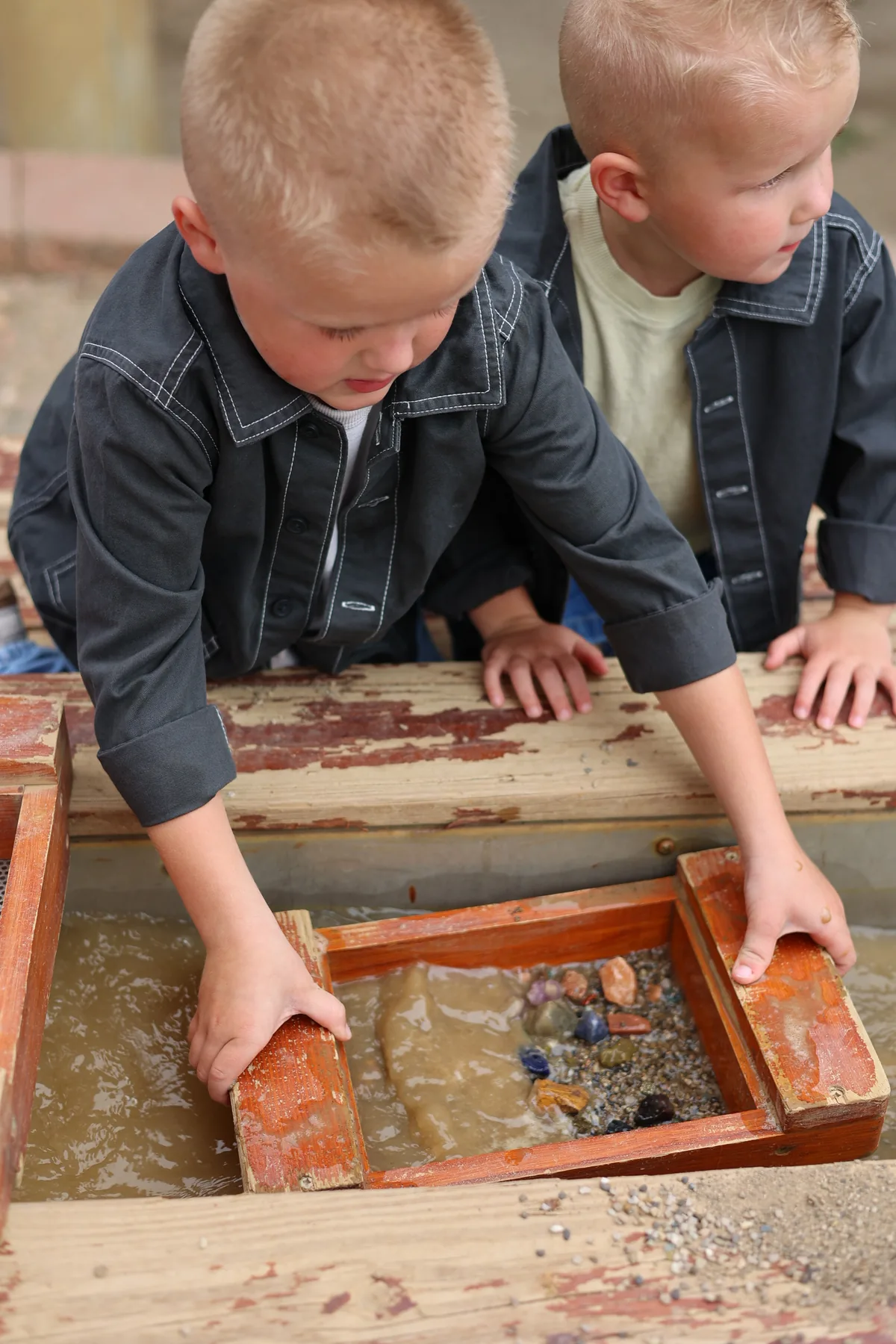 Two kids sifting for gemstones at the sluice