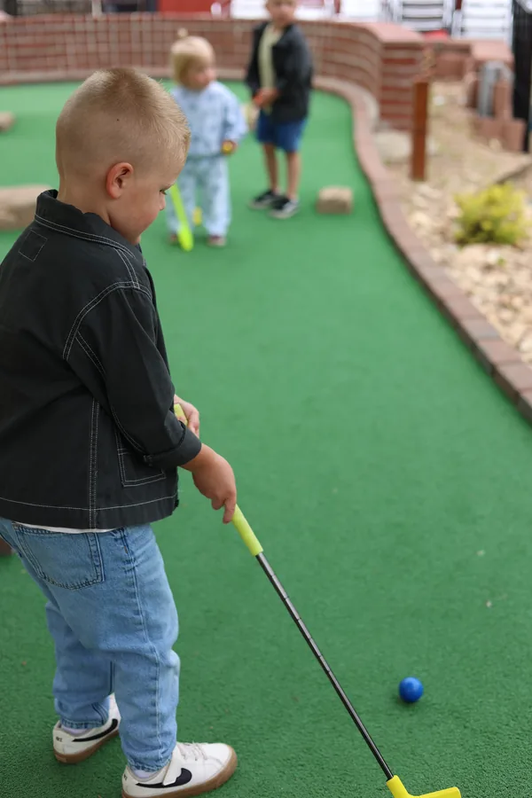 Young kids putting on the green of the Brickopolis mini golf course